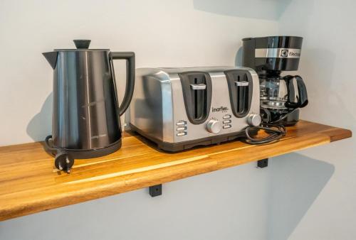 two coffeemakers and a coffee maker on a wooden shelf at Aqua Suites in Wok Tum