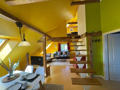 a living room with a yellow ceiling and a spiral staircase at Vogelhaus Gobbin in Lancken-Granitz
