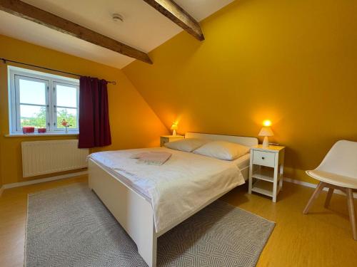 a yellow bedroom with a bed and a window at Vogelhaus Gobbin in Lancken-Granitz