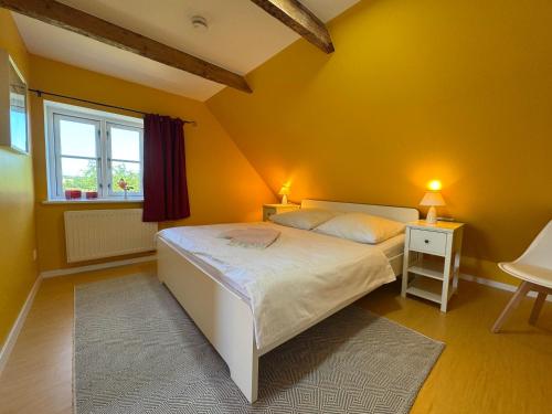 a yellow bedroom with a bed and a window at Vogelhaus Gobbin in Lancken-Granitz