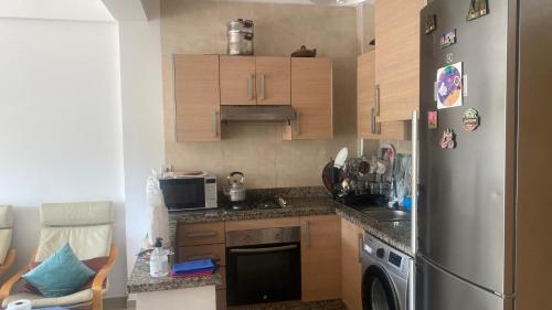 a small kitchen with a stainless steel refrigerator at Apparemment de luxe Asilah Marina Golf in Asilah