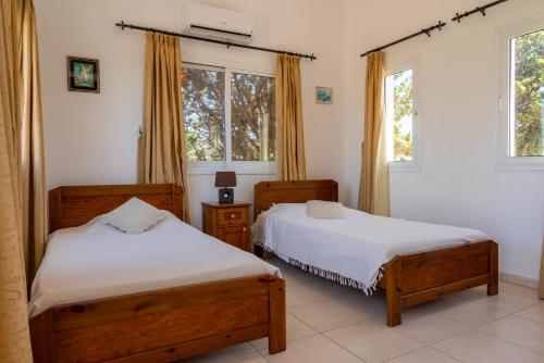two beds in a room with two windows at Villa Aspasia in Peyia, Private Pool & 3 Ensuite Bedrooms in Paphos