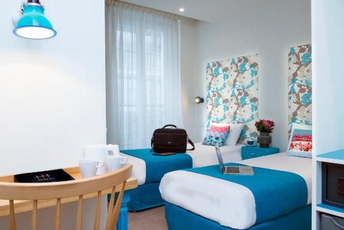 a room with two beds and a table and chairs at Hôtel Villa Bohème in Paris