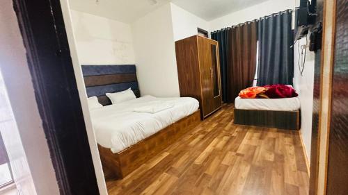 a small room with two beds and a wooden floor at Vinayak Inn Banganga Road Katra in Katra