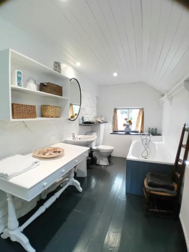 a bathroom with a sink and a tub and a toilet at Gesail Barn and Farmhouse in Machynlleth