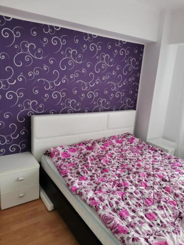 a bedroom with a bed with a purple and white wall at House Teo in Văleni