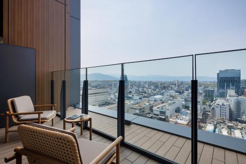 a balcony with chairs and a view of a city at One Fukuoka Hotel in Fukuoka