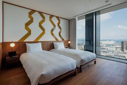 two beds in a room with a large window at One Fukuoka Hotel in Fukuoka