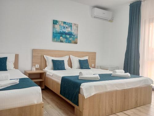 a bedroom with two beds with blue and white sheets at Vila Lorena in Mangalia