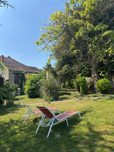 2 chaises longues et une table dans la cour dans l'établissement La cabane au fond du jardin, à Villennes-sur-Seine