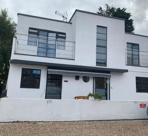 a white house with black windows at Eco Deco in Frinton-on-Sea