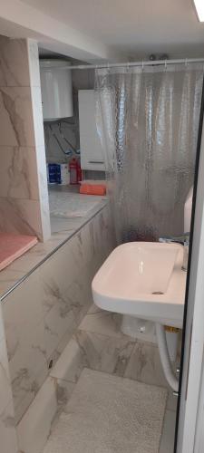 Un baño blanco con lavabo y ducha. en Apartman Asja, en Utjeha