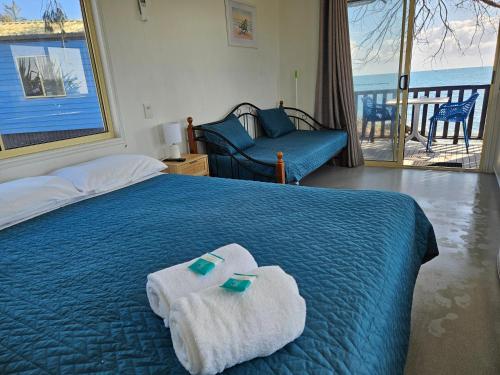a bedroom with a blue bed with towels on it at Absolute Oceanfront Tourist Park in Bargara