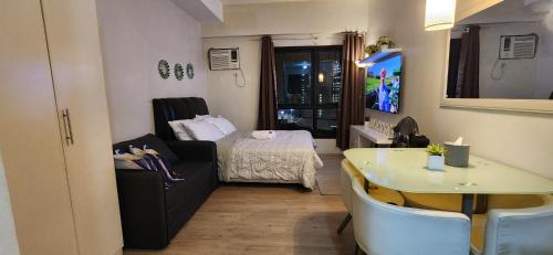 a small living room with a bed and a table at Vinia Studio for 3Pax in Manila