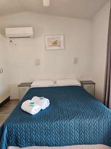 a bedroom with a blue bed with two towels on it at Absolute Oceanfront Tourist Park in Bargara