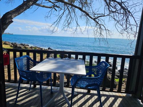 a table and chairs on a balcony with the ocean at Absolute Oceanfront Tourist Park in Bargara