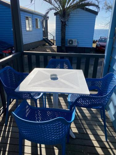 a white table and chairs on a balcony with the ocean at Absolute Oceanfront Tourist Park in Bargara
