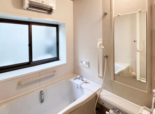 a bathroom with a tub and a sink and a window at toya町家-chitose in Toyama