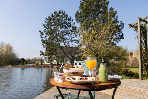 a table with food and drinks next to a body of water at Vegan B&B De Groene Mus in Wervershoof