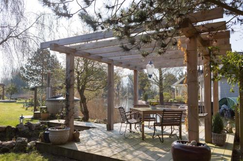 a patio with a table and chairs under a wooden pergola at Vegan B&B De Groene Mus in Wervershoof