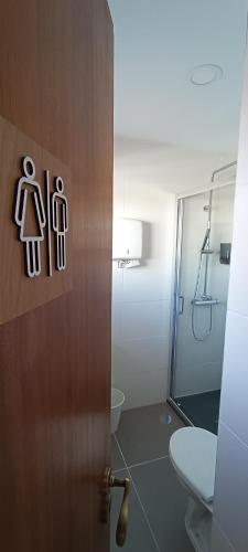 a bathroom with a shower and a door with a toilet at Faro Station Eleven Guest House in Faro