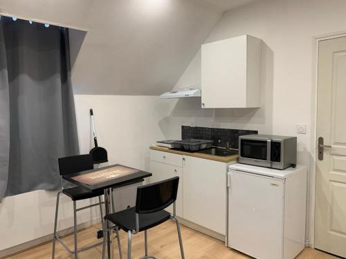 a small kitchen with a microwave and a table and chairs at Cosy Loft New-Yorkais in Guingamp