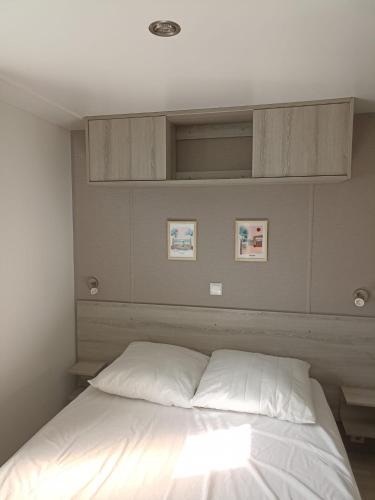 - une chambre dotée d'un lit avec des draps blancs dans l'établissement Mobil home tout confort 6 personnes, à Lacanau