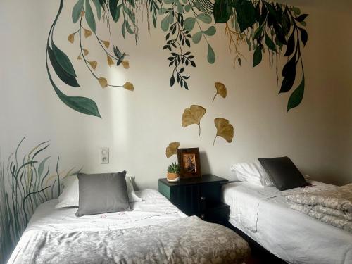 ein Schlafzimmer mit zwei Betten mit Blättern an der Wand in der Unterkunft Suditi Divine Home B&B in Lacapelle-Biron