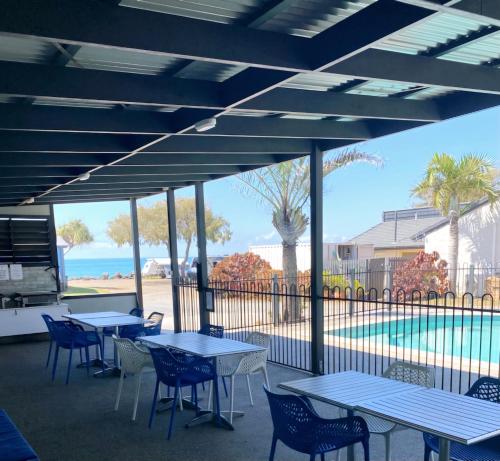 a patio with tables and chairs and a view of the beach at Absolute Oceanfront Tourist Park in Bargara