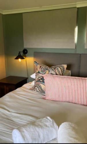 a bed with red and white pillows on it at The Pastures Eston Farm Stay in Mid Illovo