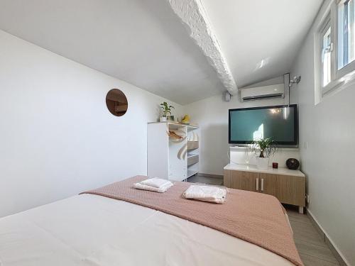 une chambre blanche avec un lit et une télévision à écran plat dans l'établissement House La Palmeraie 4p-Garden-wifi-park-jacuzzi, à Biot