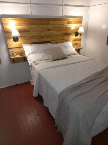 a bedroom with a large white bed with a wooden headboard at Cabana Caminho de Pedras in Montenegro