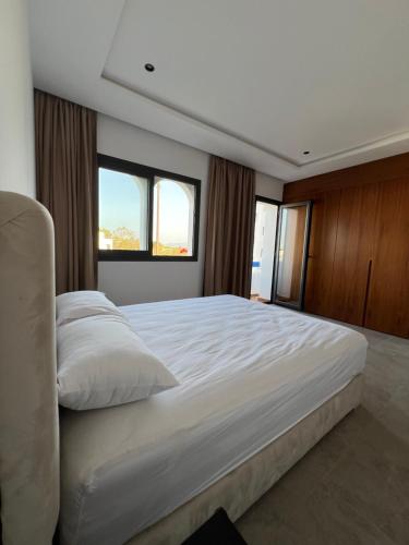 a bedroom with a large white bed with two windows at Luxury apartment near golf beach in Cabo Negro