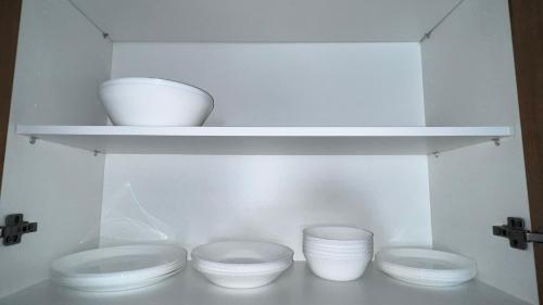 three white bowls sitting on shelves in a kitchen at Luxury apartment near golf beach in Cabo Negro