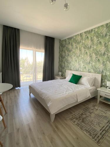 a bedroom with a white bed with a green wall at Guest House “Aura” in Cholpon-Ata