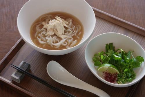 a table with two bowls of noodles and a bowl of soup at One Fukuoka Hotel in Fukuoka
