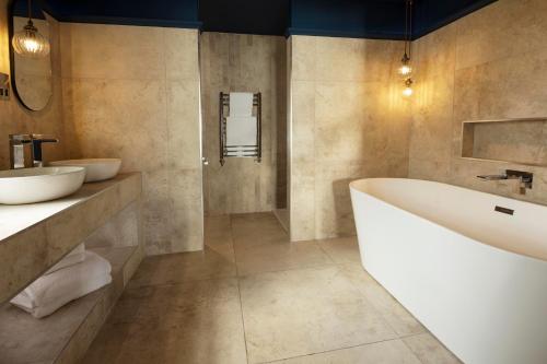 a bathroom with two sinks and a bath tub at Talland Bay Hotel, Looe in Talland