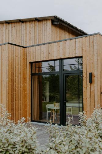 a wooden house with glass doors and a table at Hangar C gastensuites in Heers