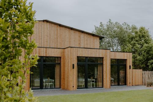 a wooden house with glass doors and a table at Hangar C gastensuites in Heers