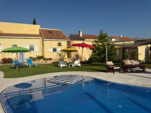 a swimming pool in a yard with chairs and umbrellas at A Casa Do Lago in Azeitao