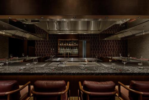 a bar in a restaurant with some chairs at One Fukuoka Hotel in Fukuoka