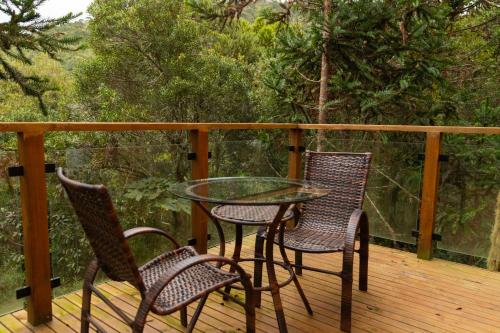 three chairs and a glass table on a deck at Cascata dos Amores in Urubici