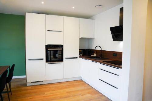 ロリアンにあるStanding & confort T3 raffiné en hypercentreの白いキャビネットとテーブル付きのキッチン