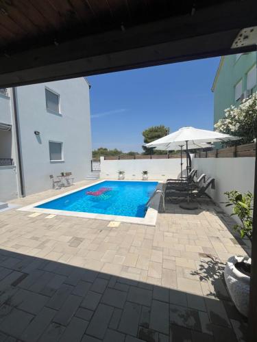 a swimming pool with an umbrella and a house at Apartment Alicia with private pool in Vodice