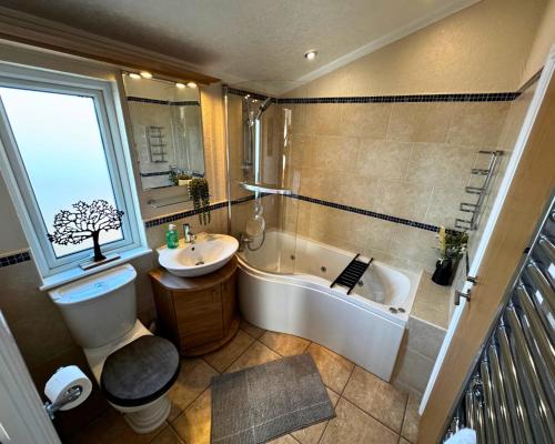 a bathroom with a tub and a toilet and a sink at Vintage 95 - Southview Holiday Park Skegness in Skegness