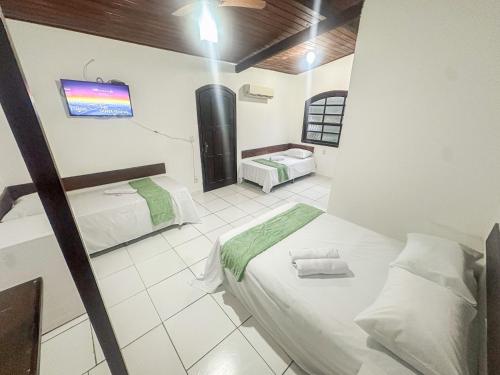 a room with two beds and a tv in it at Pousada Villa das Palmeiras in Búzios