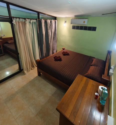 a bedroom with a bed and a wooden table at Khaosok Happy House in Khao Sok National Park