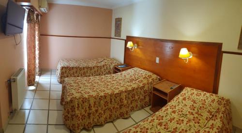 a hotel room with three beds and a tv at Hotel Francia in Tandil
