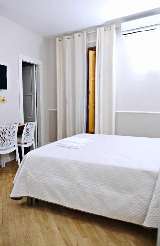 a bedroom with a white bed and a table and chairs at La Dimoraga in Chiubbica