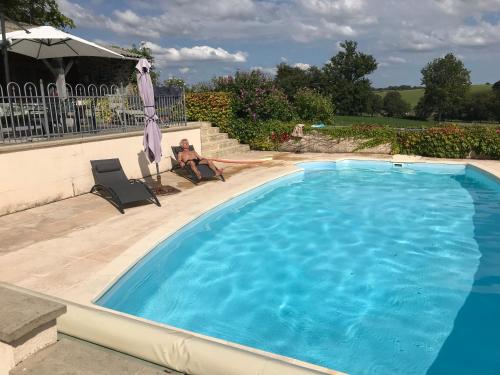 a man sitting in a chair next to a swimming pool at La Terrade in Saint-Hilaire-La-Treille